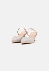 Décolleté con cinturino, caratterizzate da una punta affusolata e una tomaia argentata scintillante con strass decorativi. Cinturino color beige neutro per un maggiore sostegno.