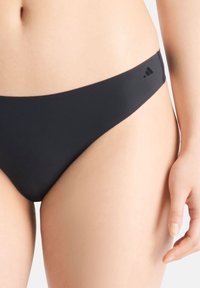 Zwarte bikini onderkant met een minimalistisch ontwerp, met een lage taille en een gladde textuur. Inclusief een klein logo op de tailleband.