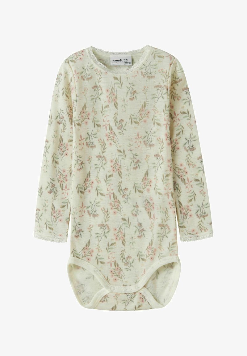 Body en manches longues jaune pâle avec un motif floral rose et vert. Tissu doux, bordure en dentelle autour du col et des manches, fermeture à pression.