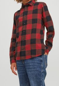 Röd och svart rutig skjorta i flanell, med knäppning framtill, långa ärmar och en avslappnad passform.