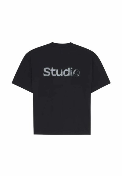 T-shirt noir à manches courtes avec le mot « Studio » en texte blanc usé dans le dos.