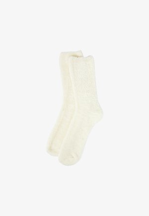 Weiche Elfenbeinsocken aus flauschigem, samtigem Material. Sie haben eine klassische Form mit geripptem Bündchen und keine sichtbaren Muster oder Akzente.