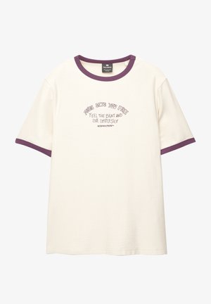 Toliko boje kreme majica s ljubičastim rebrastim okovratnikom i rukavima. Sadrži izvezeni tekst na prednjoj strani. Opušteni kroj i kratki rukavi.