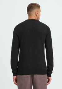 Dark gray knitted sweater with long sleeves, ribbed cuffs, and hem. Simple, minimalist design with a crew neck, viewed from the back.