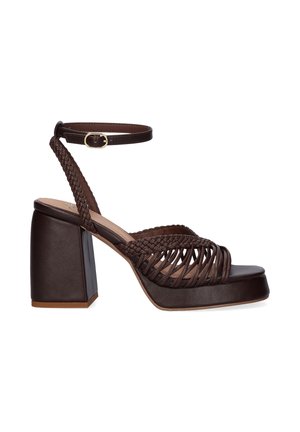 Sandalia plataforma de cuero marrón oscuro con tiras trenzadas, tacón bloque y cierre de hebilla en el tobillo sobre fondo blanco.