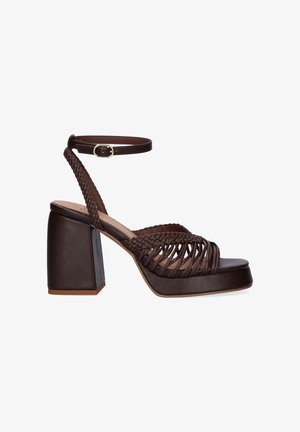 Sandalia plataforma de cuero marrón oscuro con tiras trenzadas, tacón bloque y cierre de hebilla en el tobillo sobre fondo blanco.