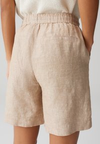 Shorts beige in lino con vita elasticizzata, dotati di due tasche laterali e una tasca posteriore, tessuto testurizzato e vestibilità comoda.