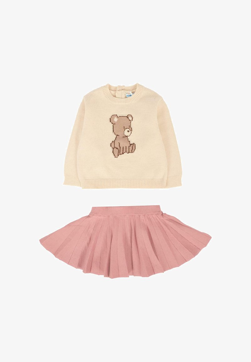 Maglione beige con un design di orsetto marrone sul davanti, abbinato a una gonna plissettata rosa. Entrambi realizzati in materiali morbidi e texturizzati.