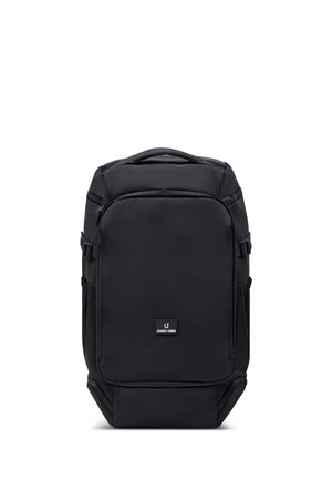 Mochila rectangular negra con asa superior, bolsillo frontal con cremallera, correas laterales y pequeño parche con el logo "Johnny Urban" en el panel frontal.