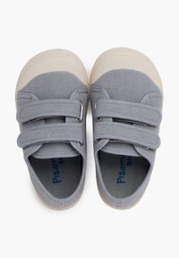 Baskets en toile grises avec un embout et des semelles en caoutchouc blanc, dotées de deux bandes Velcro pour la fermeture et d'un logo bleu à l'intérieur.