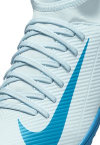 Zapatilla deportiva Nike de color azul claro con tejido texturizado, con acentos azules, cordones planos y un distintivo logo de swoosh en el lado.