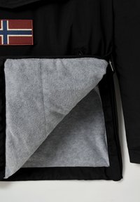 Schwarze Jacke mit einem norwegischen Flaggenabzeichen und grauem Fleecefutter, die eine glatte Außenseite und ein weiches, strukturiertes Inneres zeigt.