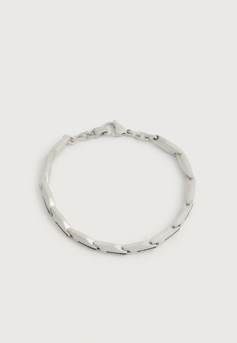 Srebrzysta bransoletka z płaskimi, kątowymi ogniwami i zapięciem typu karabińczyk, prezentowana na jednolitym jasnym tle.