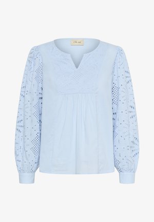 Vaaleansininen paita, jossa on lovetettu kaula-aukko, brodeerattu vartalo ja pitkät puffihihat. Sisältää yksityiskohtaisia leikkuuja sekä pehmeän ja sileän tekstuurin.