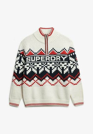 Suéter de punto crema con cuello alto, que presenta un patrón geométrico en negro y rojo. En la parte delantera muestra "SUPERDRY" en letras gruesas.