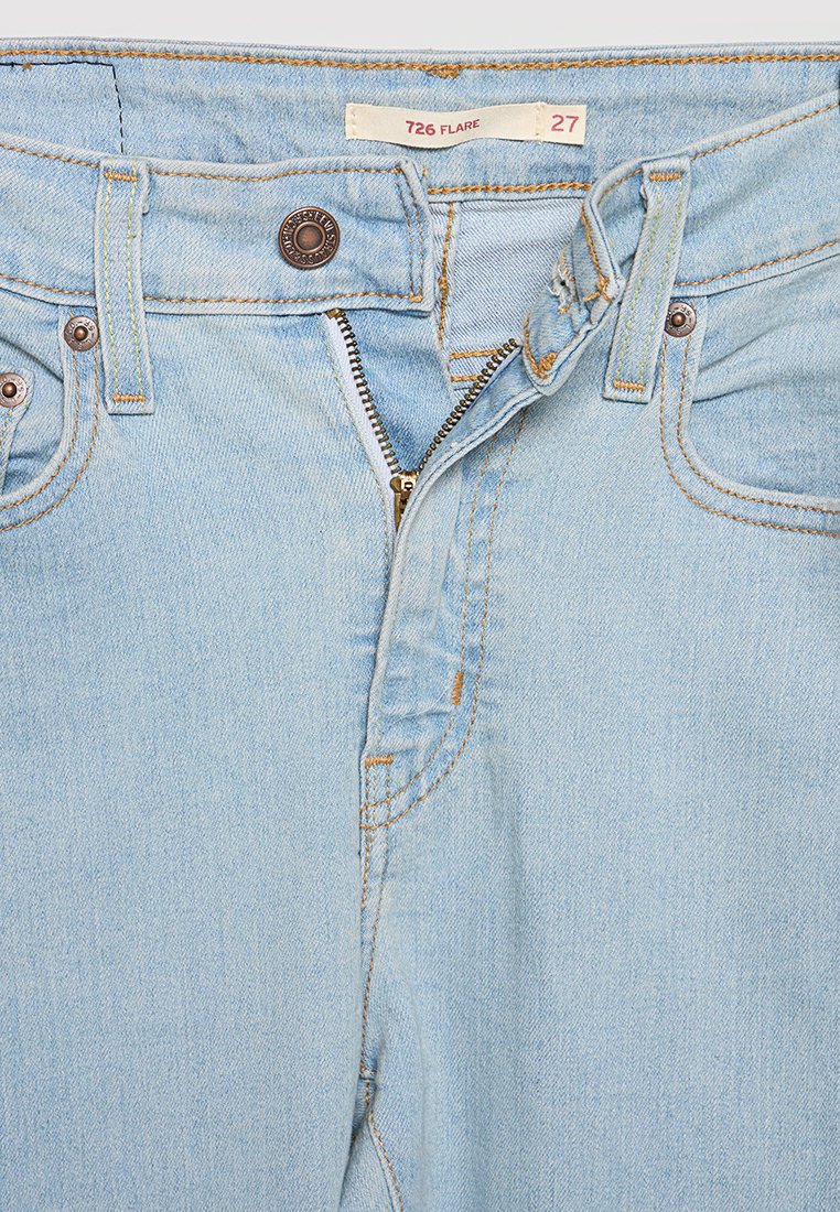 Hellblaue, schmal zulaufende Jeans mit weitem Bein, Reißverschluss, Kupferknopf, kontrastierenden Nähten und dezenten Gebrauchsspuren in der Nähe der Taschen. Größenetikett: 27.
