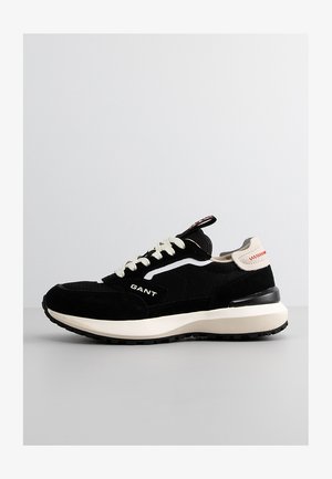 Black suede and mesh sneaker with white accents and textured rubber sole. Features a beige heel counter and logo detail on the side.