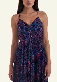Floral-patterned dress with thin straps, gathered bodice, and flowing skirt in shades of purple, blue, and pink. Smooth texture.