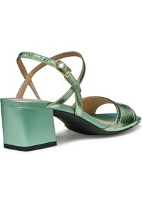 Sandalias de tacón verde menta con tiras cruzadas y acabado texturizado. Presenta un tacón cuadrado y un forro interior suave.
