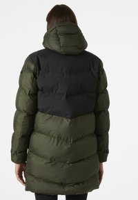 Abrigo de plumas en verde oliva y negro con cuello alto, patrón de acolchado en forma de chevrón y textura suave. Cuenta con capucha y diseño alargado.