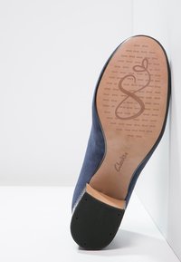 Chaussure bleu marine avec tige en suède doux, bout arrondi et semelle en caoutchouc avec un motif tactile. Logo Clarks imprimé sur la semelle intérieure.
