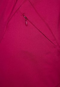 Top sportivo fucsia con texture liscia, design angolato e tasca laterale con zip per riporre oggetti.