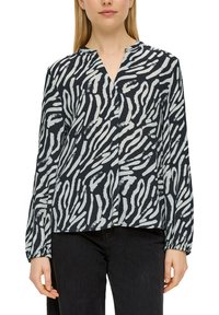 Langärmlige Bluse mit V-Ausschnitt, die mit einem schwarz-weißen abstrakten Zebramuster gestaltet ist. Hergestellt aus leichtem Stoff, mit gerafften Manschetten.