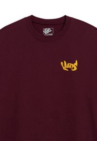 Burgundy cotton t-shirt with a round neck, featuring an embroidered yellow "Vans" logo on the left chest area.