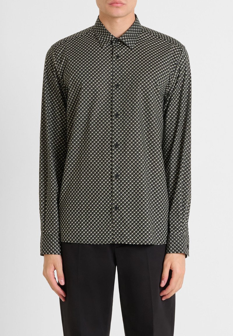 Camicia a maniche lunghe di colore verde scuro con un motivo geometrico in crema e nero. Presenta un colletto a punta e una chiusura con bottoni. Tessuto testurizzato.