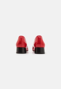 Red patent leather shoes with a rounded toe and small black block heels, featuring a smooth texture and sleek design.