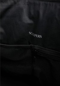 Interior de bolsa de tela negra con un bolsillo de malla y logo en relieve "SCALPERS" en blanco. Textura suave con un compartimento con cremallera.