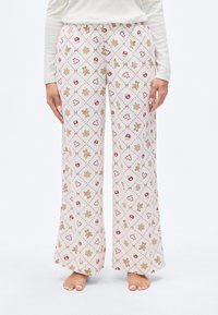 Άσπρο παντελόνι πυτζάμας με επαναλαμβανόμενο μοτίβο από ανδράκια τζίντζερμπρεντ, καραμέλες μπαστούνια και εορταστικά εικονίδια σε κόκκινους και καφέ τόνους. Ελαστική μέση.