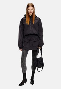 Giacca nera con cappuccio, zip frontale, vita elastica e due tasche frontali; abbinata a leggings grigi con strisce laterali e stivali neri.