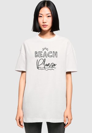 Valge puuvillane T-särk laia lõikega, millel on must tekst "BEACH Please" koos päikese ja laine graafikaga. Lühikesed varrukad, ümmargune kaelus.