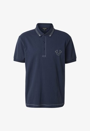 Námořnicky modrá polokošile s krátkým rukávem, bílým prošitím na límci, légu s knoflíky, lemu a logem ve tvaru podkovy na levé straně hrudi.