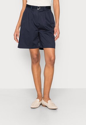 Shorts bleu marine avec un devant plissé, dotés d'une ceinture noire avec une boucle en argent. Fabriqués en tissu léger, design à longueur genou.