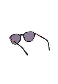 Gafas de sol negras con lentes redondos, tinte gris y acabado brillante. Las piernas presentan acentos en rojo y azul con detalles en hardware dorado.
