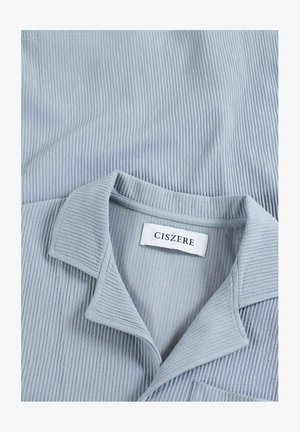 Lichtblauwe overhemden met een ribbeltextuur, voorzien van een borstzakje en een label met de tekst "CISZERE" gestikt aan de binnenkant.