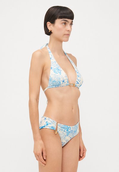 Bikini komplektas su halter tipo viršumi, mėlynais gėlių raštais, giliu iškirpimu ir atitinkančiais žemais apatiniais su auksiniais akcentais. Lygus audinio paviršius.