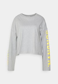 Gray cropped long-sleeve shirt made of soft cotton. Features bold yellow text along the right sleeve. Round neckline, loose fit.