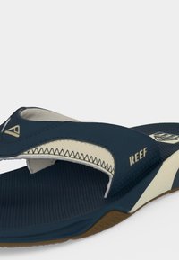 Sandale tong Reef bleu marine et beige avec une semelle intérieure rembourrée, une semelle texturée et une bride réglable avec des détails du logo.