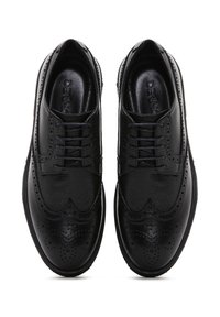 Chaussures habillées en cuir noir avec un design à bout fleuri, des détails en brogue et une texture lisse, fermées par lacet.