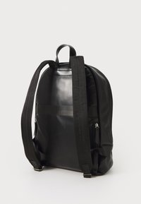 Zaino in pelle nera con spallacci in tessuto regolabili, superficie liscia, due zip laterali e una maniglia superiore per una facile portabilità.