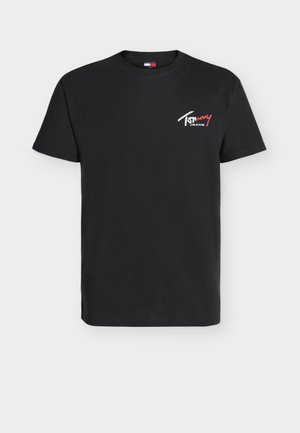 Camiseta negra de manga corta con cuello redondo y pequeño logo blanco y rojo de "Tommy Jeans" en la parte superior izquierda del pecho.