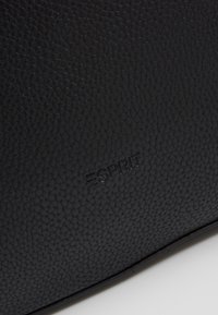 Svart texturerad läderväska med präglad "Esprit"-logotyp, rektangulär form med mjuka kanter och en slitstark yta.