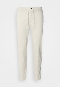 Ljust beige tapered byxor gjorda av mjukt bomullstyg, med elastisk midja, snörning i midjan och sidfickor.