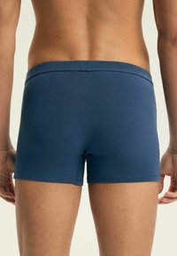 Granatowe szorty z elastycznego materiału o gładkiej fakturze. Projekt wyróżnia niski stan pasa oraz dopasowany krój wokół ud.