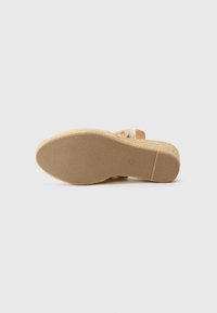Kilvall sandal med en texturerad beige sula och ljusa remmar. Har en kurvad design med ett vävt accentuering på hälen.