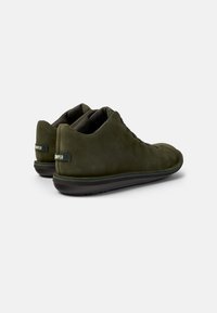 Sneakers verde in suede con profilo basso, punta rotonda, suola in gomma nera e dettaglio di branding laterale. Texture liscia e design con lacci.