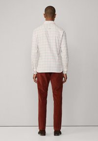 Wit geruit overhemd met lange mouwen met een rood en blauw ruitpatroon, gecombineerd met roestkleurige corduroy broek. Zachte textuur en slim fit.